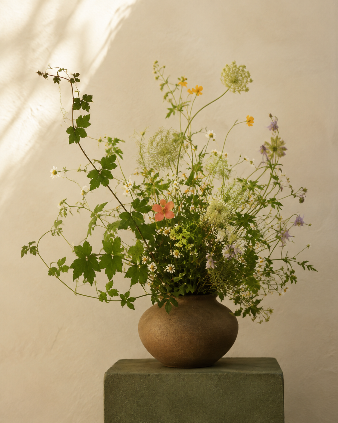 Airy green stems and delicate white, yellow and lilac flowers in a ceramic vase